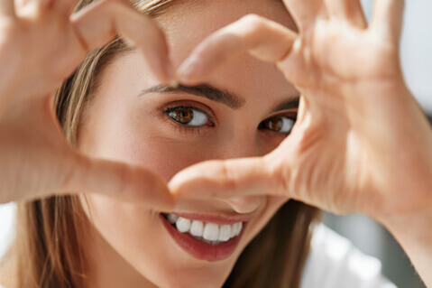 Young woman looking through her fingers in a heart shape